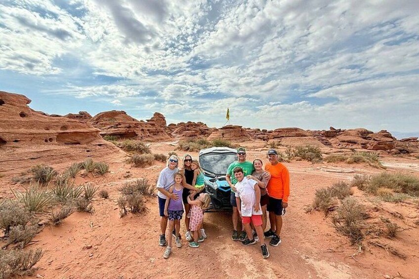 A group of people standing in a desert with red rock formations and a clear sky. 3