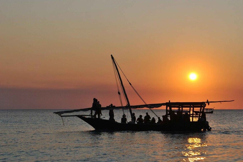 A traditional boat with people on a calm sea during sunset. 2