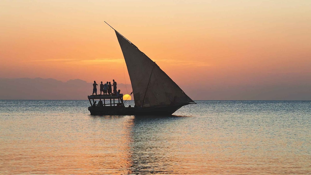 A boat with a sail on the water during sunset. 1