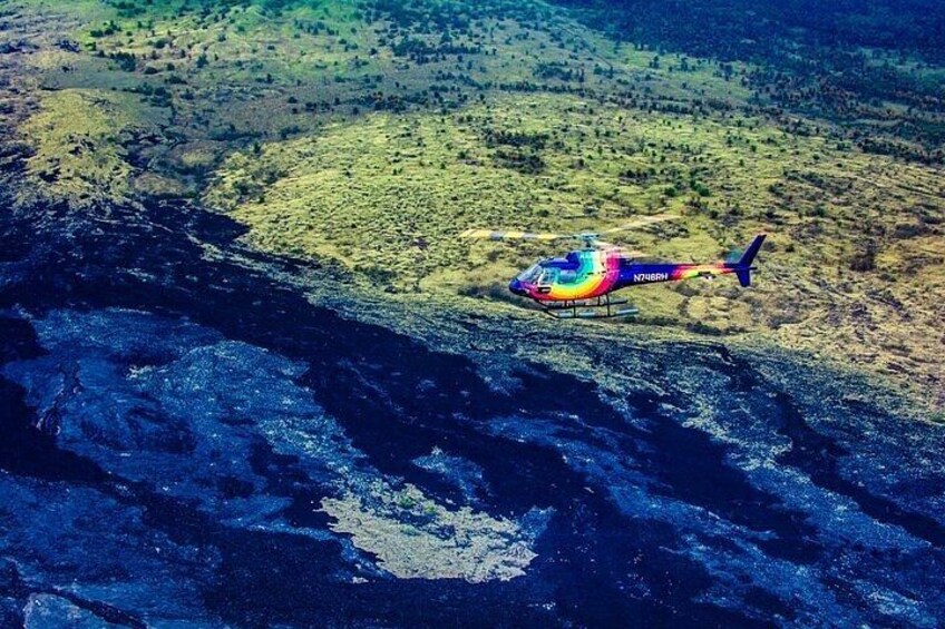 Ein Hubschrauber fliegt über einer gebirgigen Landschaft, darunter fließt ein Fluss. 1
