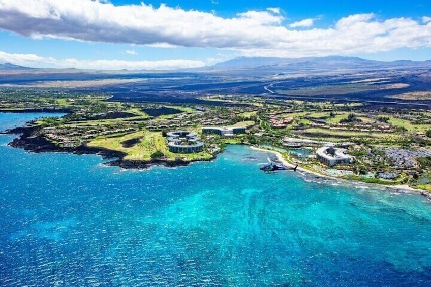 An aerial view of a coastal area with clear blue waters, a helicopter, and a circular building complex. 4