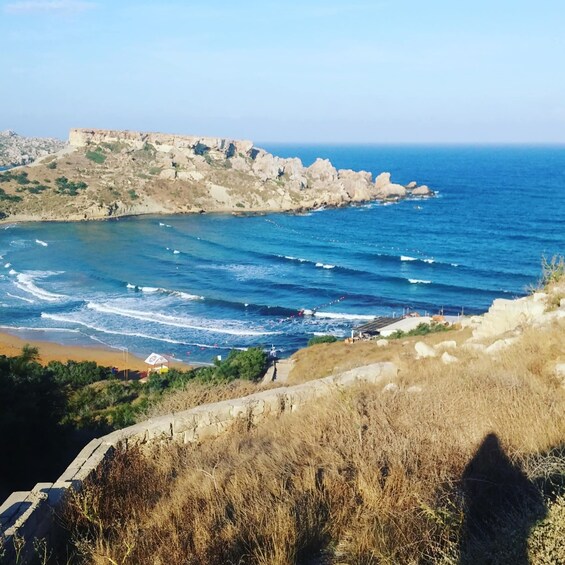 A coastal landscape with rocky cliffs, a beach, and waves. 3
