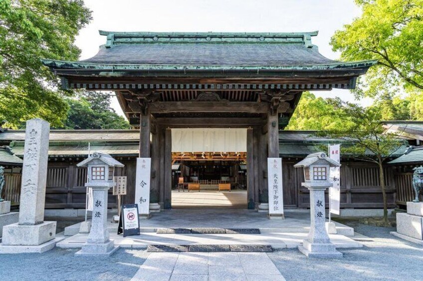 A traditional Japanese gate with stone lanterns and a wooden building in the background. 5