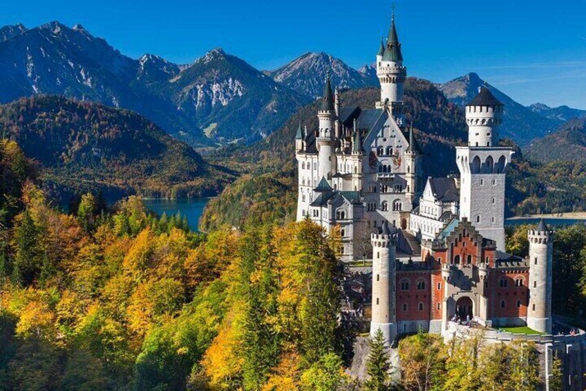 A castle surrounded by mountains and autumn foliage. 1