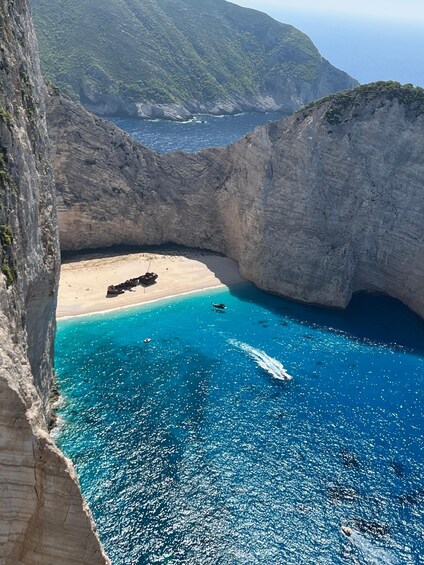 A coastal landscape with a beach, clear blue waters, and rocky cliffs. 4