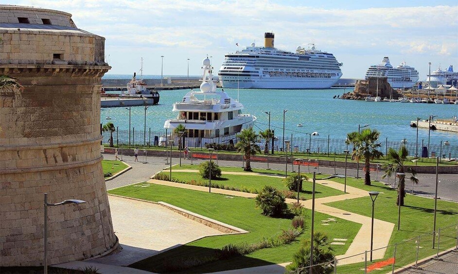 A harbor with cruise ships, a historic tower, and a landscaped promenade. 1