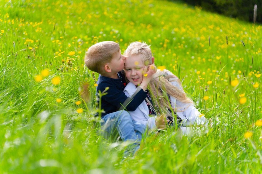 Two children sitting in a field of yellow flowers. 1