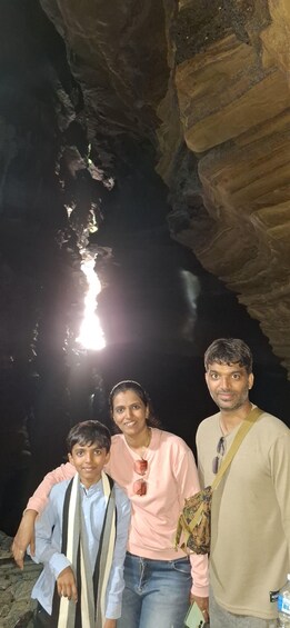 Three people standing in a cave with a light reflecting off the water. 5