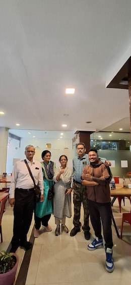 A group of people standing indoors in a modern restaurant with a glass partition and wooden furniture. 2