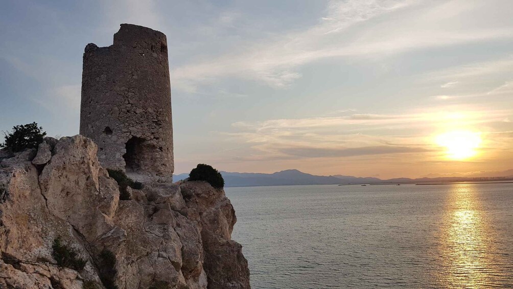 A coastal ruin with a tower, rocky cliffs, and a sunset over the sea. 2