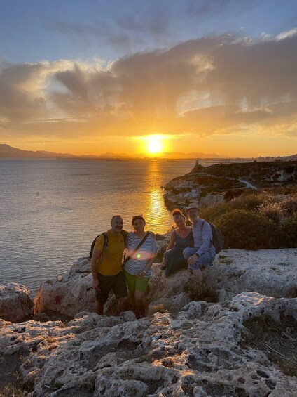 A sunset over a body of water with a rocky coastline and a small settlement. 5