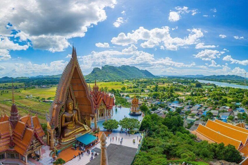 A temple complex with a large Buddha statue, surrounded by traditional architecture and a river. 4