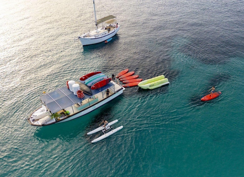 A sailboat docked with several paddleboards and a person paddleboarding nearby. 1