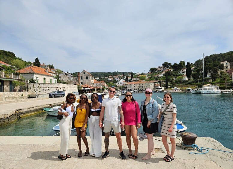 A group of people standing by a waterfront with boats, buildings, and a clear sky. 2