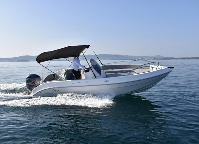 A motorboat with a canopy, moving on calm water with a clear sky. 5