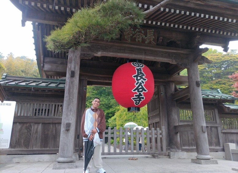 A traditional Japanese torii gate with a red lantern and a person standing beneath it. 2