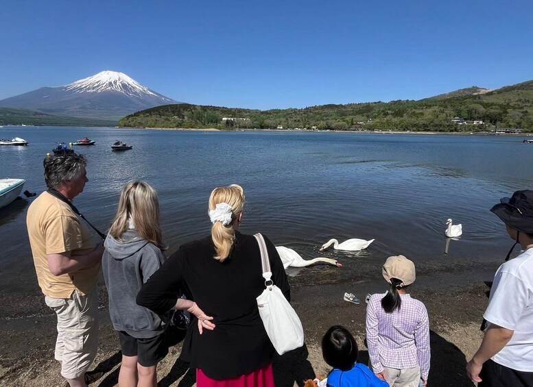 A group of people by a lake with a mountain in the background. 2