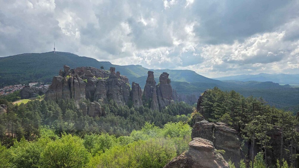 A mountainous landscape with prominent rock formations and a distant tower. 4