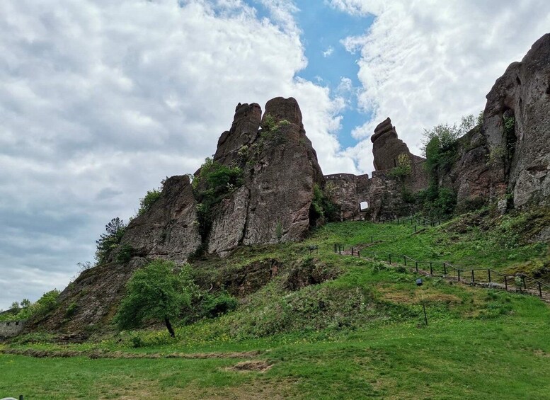 A rocky landscape with prominent cliffs and a grassy hill. 1