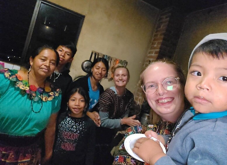 A group of people indoors, some holding plates, with a brick wall and a door in the background. 1