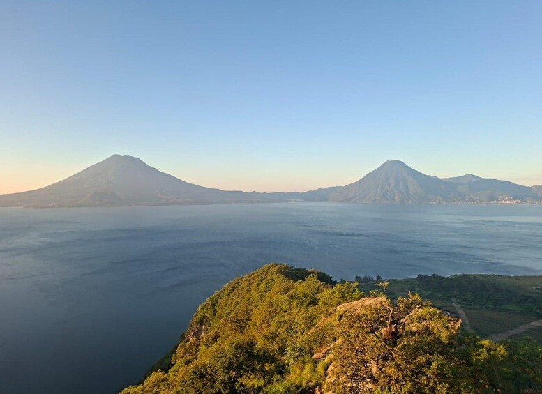A mountainous landscape with two prominent volcanoes and a body of water in the foreground. 2