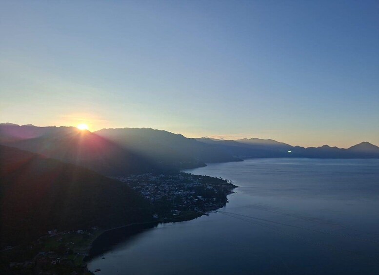 A coastal landscape with a sunrise, mountains in the distance, and a calm sea. 3