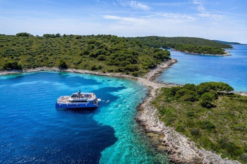 A boat on a clear blue sea with a coastline of green vegetation. 1