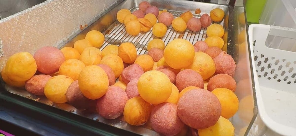 A tray of round fruits, some yellow and some pink, being cooked on a grill. 3