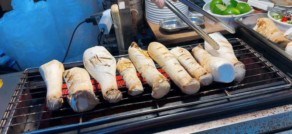 A grill with several skewers of meat being cooked over direct flames. 5