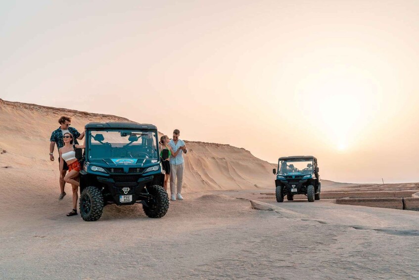 Two off-road vehicles on a desert road with people standing beside them. 3
