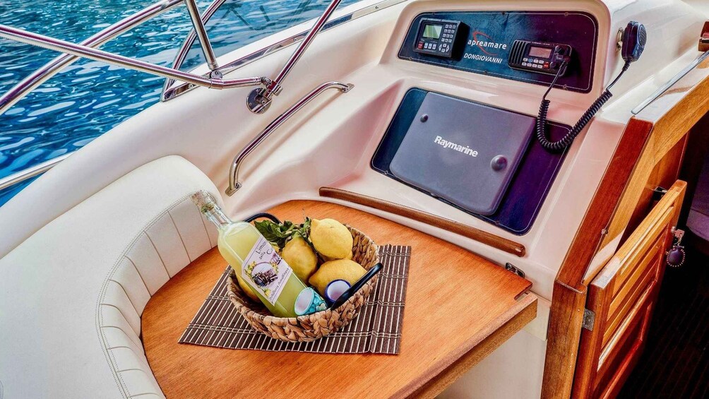 A boat's interior with a control panel, a 'Raymarine' device, and a basket with lemons and lemons. 2