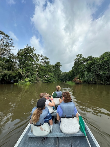 A group of people in a boat on a river surrounded by dense greenery. 2