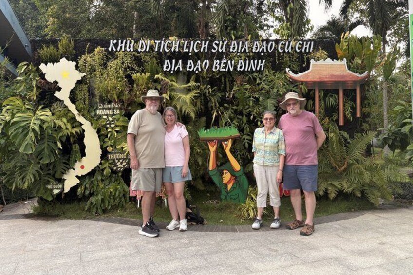 A group of people standing in front of a map and a traditional pavilion. 2