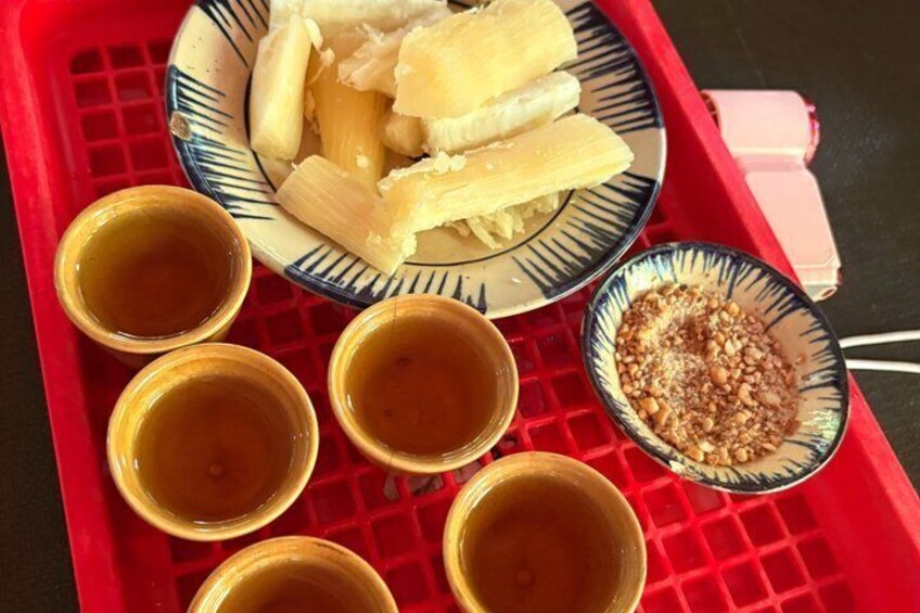 A red tray with a plate of bananas, a bowl of nuts, and four small bowls of a brown liquid. 5