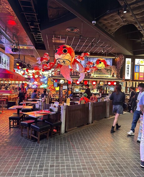 A bustling indoor market with tables, chairs, and hanging decorations. 2