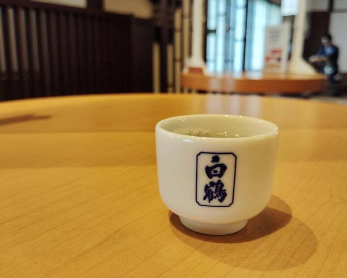 A white ceramic cup with Japanese characters on a wooden table. 3