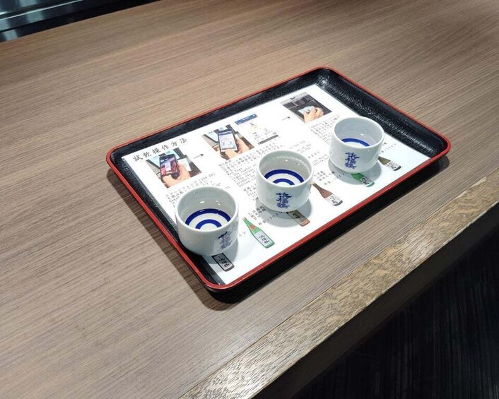 A tray with three cups and a booklet on a wooden table. 1