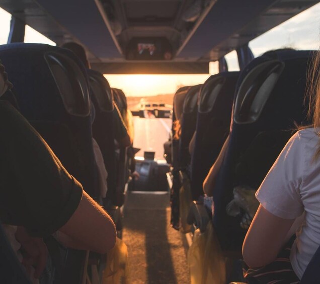 The interior of a bus with rows of seats and a view of the sunset through the windows. 3