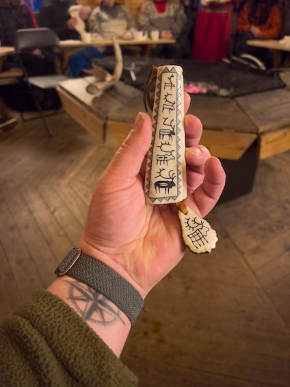A hand holding a carved wooden object with inscriptions. 4