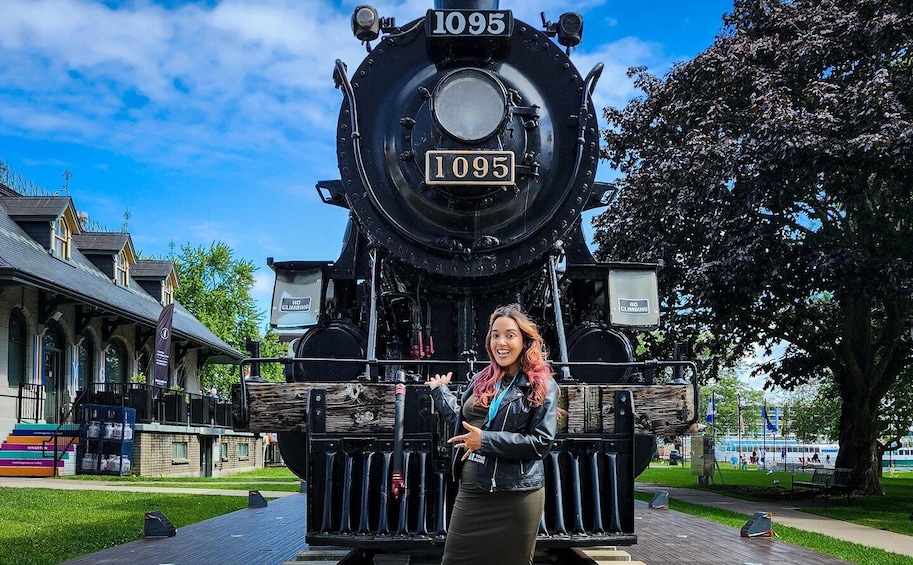 A model train with the number 1095, a person standing in front of it, and a building with a 'NO CLIMBING' sign in the background. 4