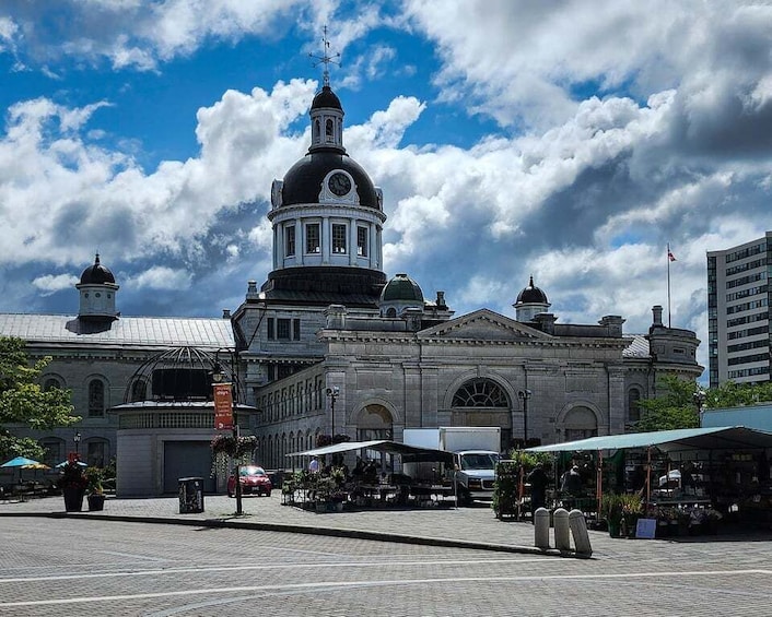 A historic building with a prominent dome and clock tower, surrounded by outdoor cafes and a clear sky. 3