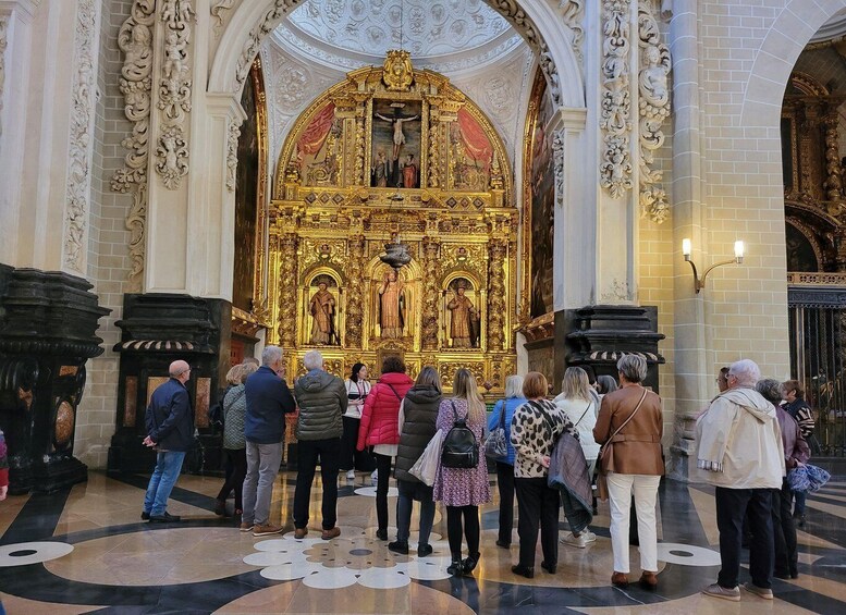 A group of people inside a church with ornate golden altars and a large crucifix. 2
