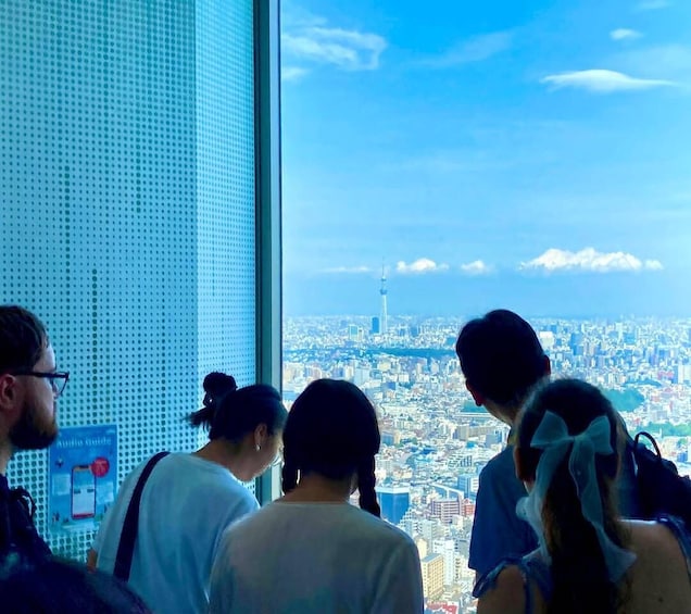 A group of people looking out from a high-rise building at a cityscape with a prominent tower. 2