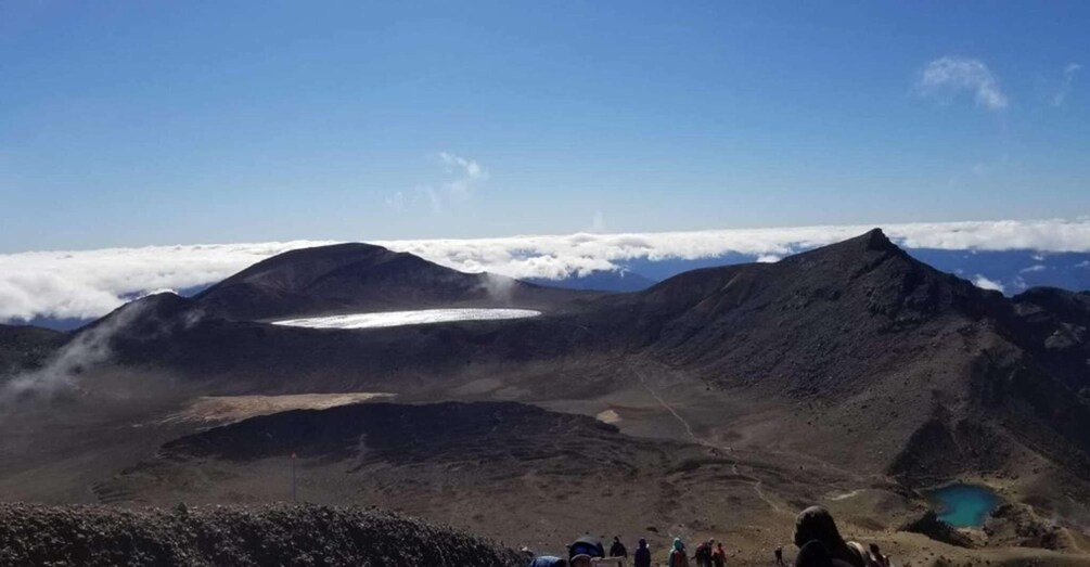 Ett bergigt landskap med en glaciär, en liten sjö och en grupp vandrare. 5