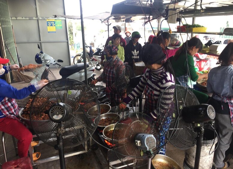 A group of people cooking outdoors with large fans and cooking equipment. 3