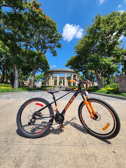 A bicycle parked in front of a historical monument with trees and a clear sky. 3