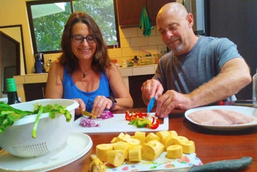 Two people preparing food with vegetables and chicken in a kitchen. 2