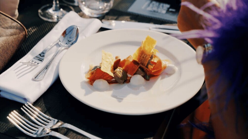A white plate with a dish of food, a fork, and a spoon on a table. 3