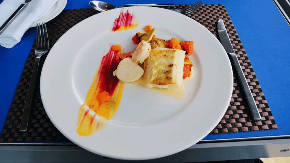 A plate with a dessert, possibly ice cream, on a table with a blue tablecloth and a woven placemat. 5