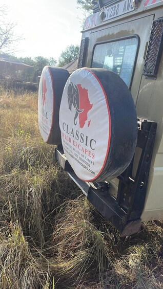 A vehicle with two large, round, white signs with red and black text advertising 'CLASSIC WILDLESCAPES.' 2